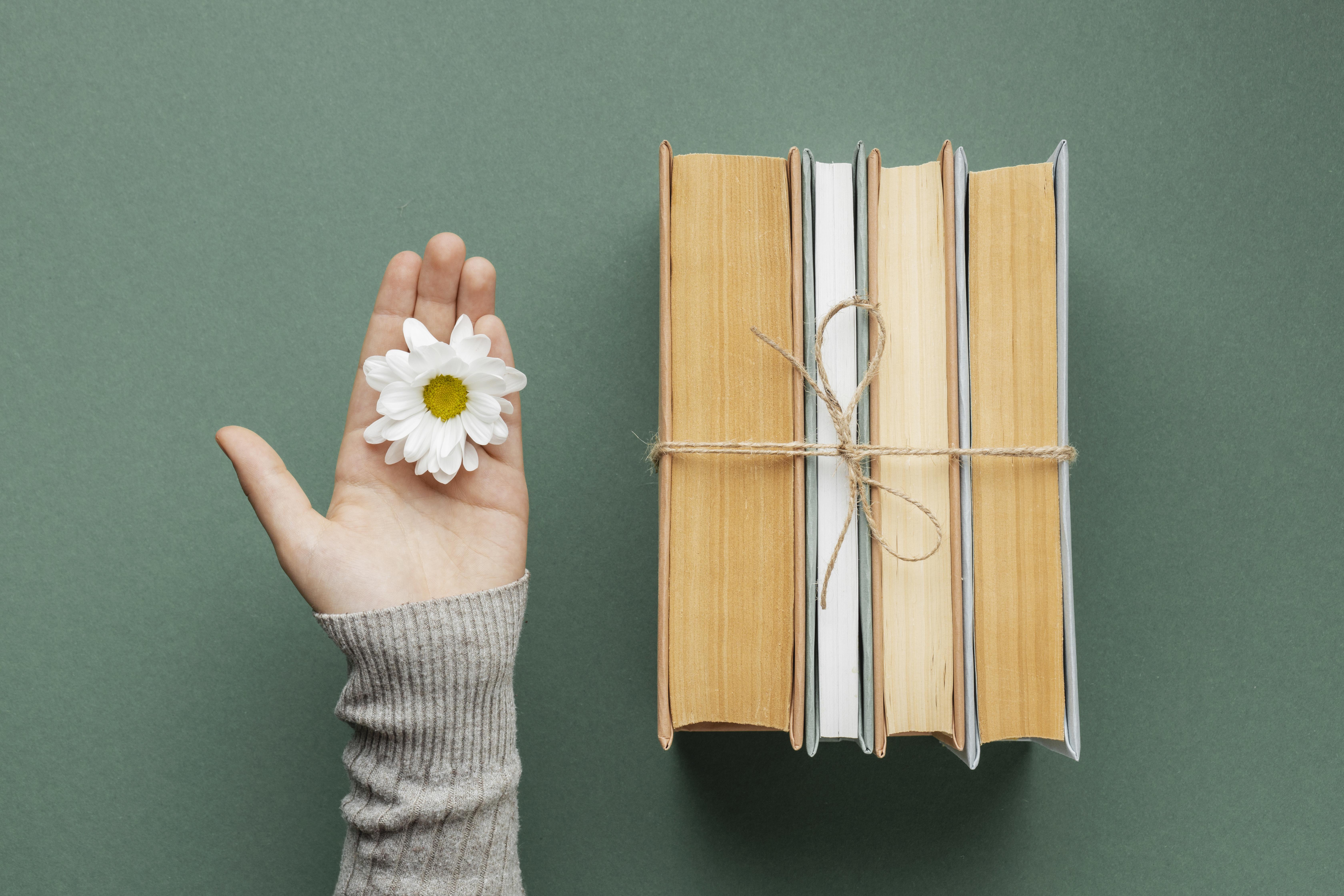 Una mujer con una flor en la mano y a la lado los mejores libros de crecimiento persona y espiritual.