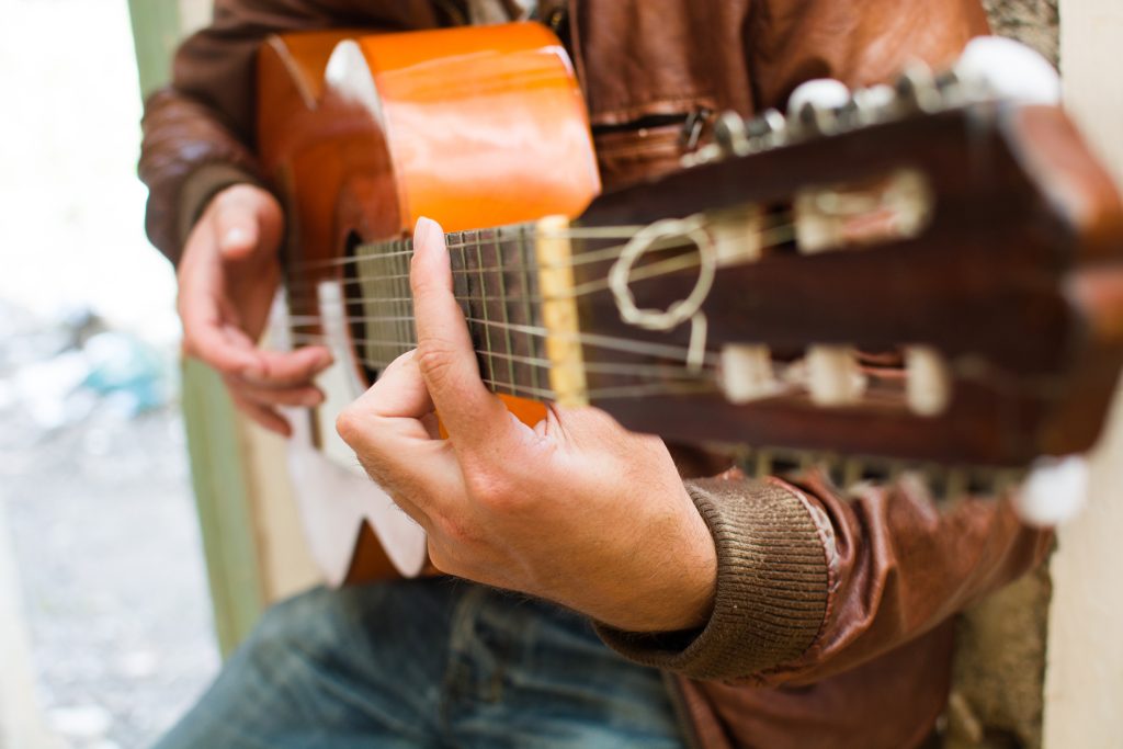 Un hombre tocando la guitarra española, mientras tararea una canción popular española antigua